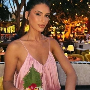 Pink satin slip maxi dress with lace-up details shown in a luxury restaurant setting