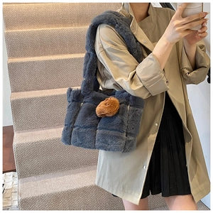 Detail of blue-grey quilted plush tote bag featuring a cute brown animal charm