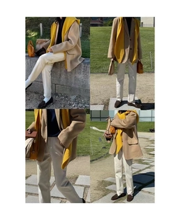 Detail shot of a stylish beige blazer paired with a vibrant yellow knitted scarf outdoors