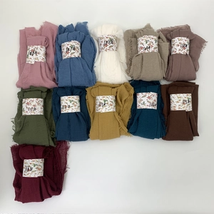 Flat lay of multiple colorful pleated cotton viscose shawls with floral paper labels