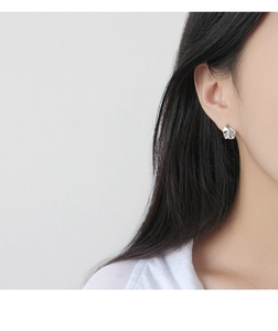 Détail d'un mannequin portant des boucles d'oreilles argentées géométriques irrégulières