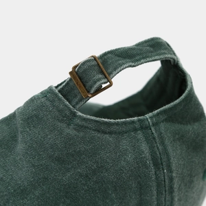 Detail of adjustable metal buckle and vintage washed cotton fabric on green baseball cap