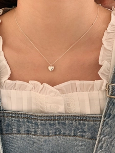 Detail of silver heart pendant with star engraving worn on a model's neck