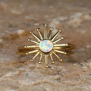 Macro detail of sunburst ring with central opal stone and golden rays on natural rock