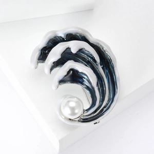 Détail de la broche vague en émail bleu ornée d'une grande perle blanche centrale
