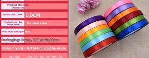 Detail view of 1cm polyester satin ribbons in multiple colors on beige linen background