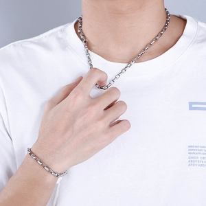 Close-up of silver square link chain necklace and bracelet set worn by a male model