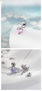 Detail of dual heart-shaped zircon earrings with secure screw-back design on floral card