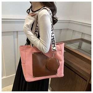 Pink canvas travel tote with brown leather pocket and round coin purse on shoulder strap