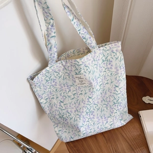 Détail du sac cabas en coton avec motif floral violet et étiquette tissée blanche