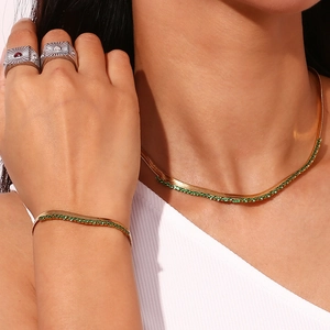 Detail of 18K gold plated herringbone chain necklace and bracelet with green zircon