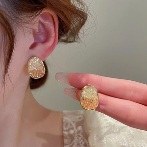 Detail of amber gradient resin stud earrings with gold trim and crushed ice texture