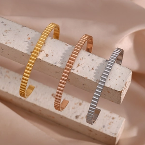 Detailed view of striped stainless steel open bangles in gold, rose gold and silver