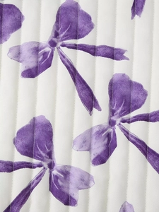 Macro shot of vertical quilted white fabric featuring purple bow-knot print details