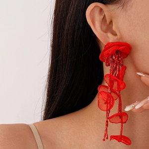 Detail of red handmade lace flower earrings with beaded tassels on model's ear