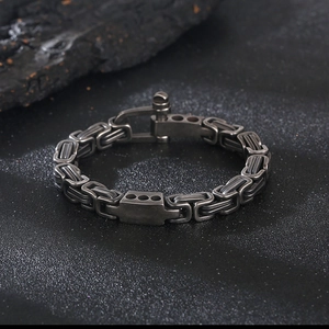Detailed view of gunmetal Byzantine chain bracelet with horseshoe buckle on dark stone