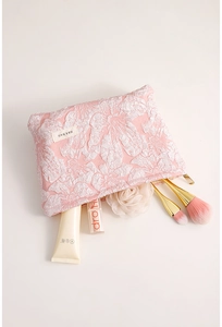 Detail of pink floral jacquard makeup bag with gold zipper and embossed flower patterns
