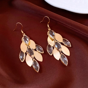 Detail of gold leaf earrings with marquise crystals on elegant brown silk background
