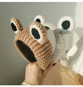 Close-up of hand-knitted frog headbands in brown and beige with 3D eye details