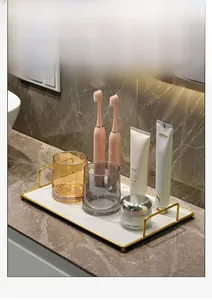 Detail of a rectangular marble vanity tray with gold handles for bathroom organizers