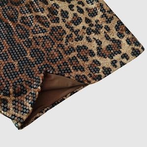 Detailed close-up of leopard print fabric with dense sequins and brown inner lining