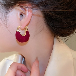 Close-up of vintage red flocked U-shape earring with gold clasp on a model ear
