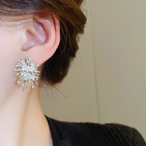 Close-up of sparkling silver firework earrings with inlaid zircons on a female model