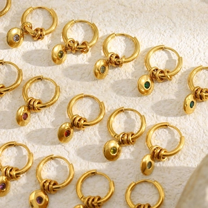 Détails de boucles d'oreilles créoles dorées avec pierres de naissance sur support en pierre