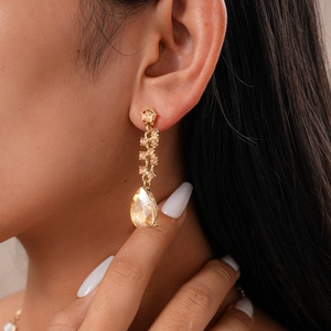 Detailed close-up of champagne teardrop crystal earrings with elegant gold plating