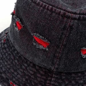 Detailed macro shot of distressed denim bucket hat featuring red fringe stitching