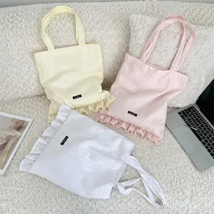 Close-up of three striped canvas tote bags with ruffle trim in yellow, pink, and white