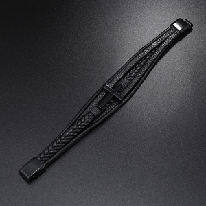 Macro detail of multi-layer black braided leather cord and matte metal cross magnet clasp