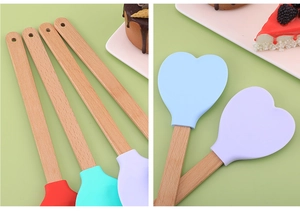 Detail of four heart-shaped silicone spatulas with wooden handles in vibrant colors