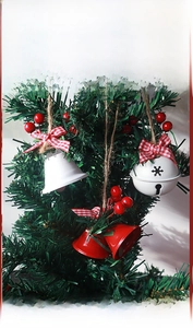 Close-up of white and red Christmas bells with berries and bow on a tree branch