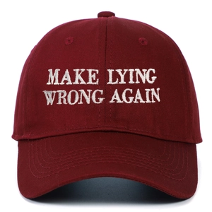 Dettaglio del ricamo bianco 'MAKE LYING WRONG AGAIN' su un cappellino di cotone bordeaux
