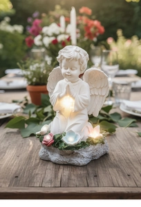 Estatua de ángel solar rezando con cruz brillante y flores LED en un entorno de jardín