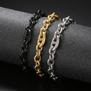 Three-color Cuban chain bracelets in black, gold, and steel hanging on a display