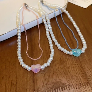 Detail of double-layer faux pearl choker with pink and blue beads and iridescent heart charm