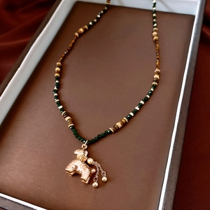 Détail du collier de perles avec pendentif caniche doré et perles d'œil de tigre décor