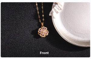 Detailed close-up of golden clover pendant with pink zircon on black background