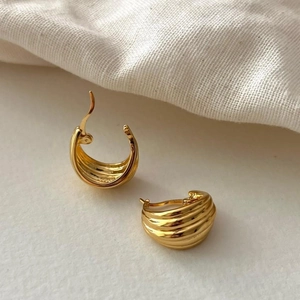 Detail of golden textured geometric earrings showing refined metallic luster and design