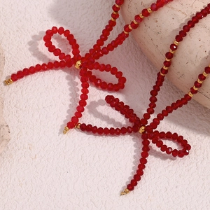 Macro shot of red faceted beads and gold metal accents on a bow pendant necklace