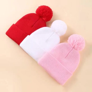 Dettaglio della maglia di berretti invernali rosso, bianco e rosa con pompon