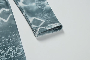 Detail of sleeve cuff with geometric ethnic print on elastic tie-dye knit fabric