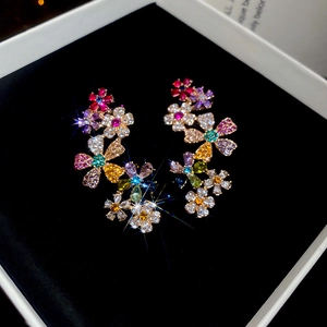 Macro detail of 18k gold plated floral earrings with colorful crystals on black velvet