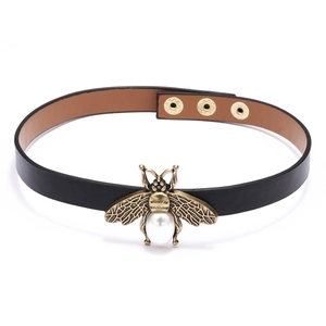 Detail of a vintage faux leather arm guard featuring a bronze bee with pearl inlay