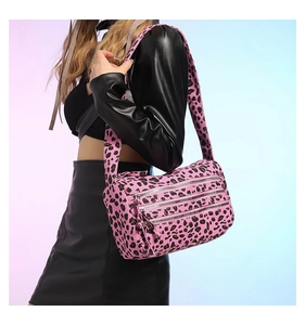 Gros plan d'un sac cabas léopard rose avec trois fermetures éclair argentées et tissu