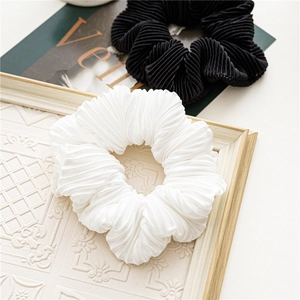Detail view of white and black pleated fabric scrunchies on a vintage wooden frame