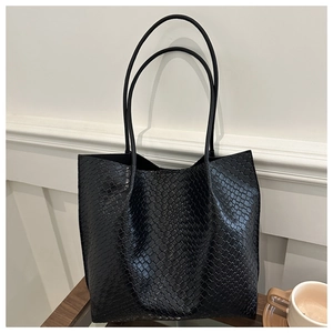 Close-up of black woven texture on large tote bag with slender straps on wooden table