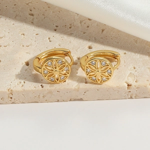 Makroaufnahme goldener Blumenohrringe mit Zirkonia auf einer Steinoberfläche